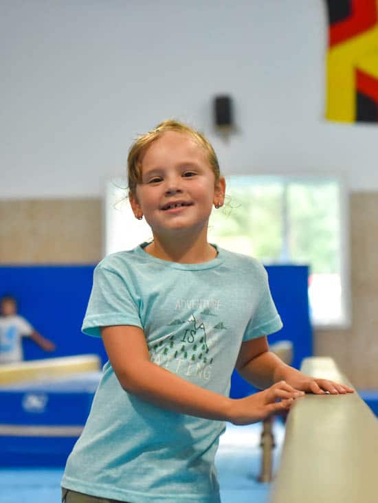 Girl smiling while walking next to balance beam