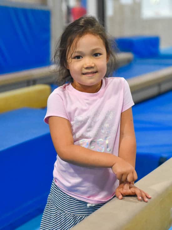 Girl smiling next to balance beam