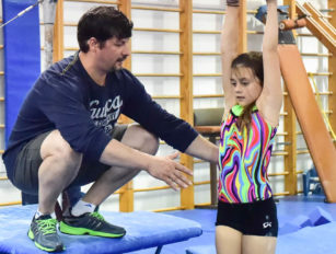 Coach helping girl on the bars